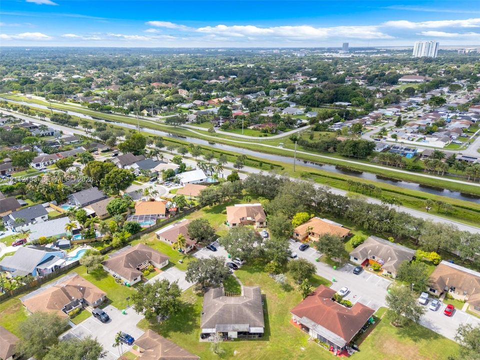 Aerial perspective of a suburban landscape featuring a canal, paved residential streets, mature trees, and detached single-family dwellings