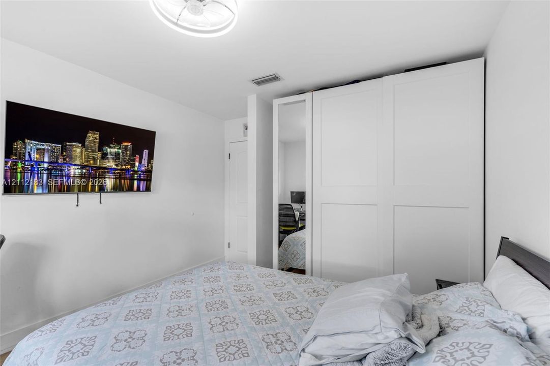 Built-in white shaker-style wardrobe featuring a full-length mirrored panel and a ceiling-mounted circular light fixture