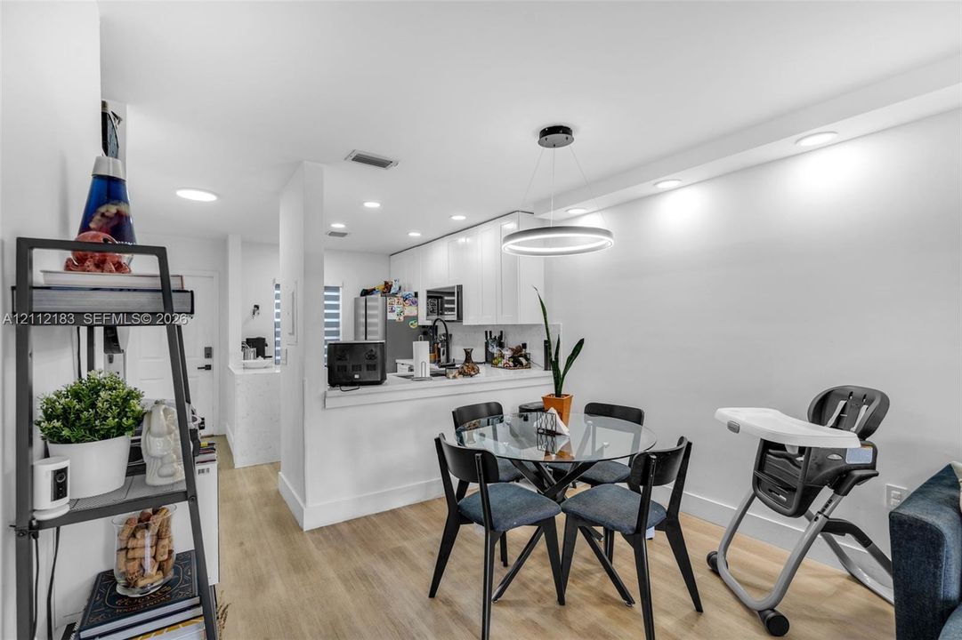 Kitchen area featuring white cabinetry, wood-finish flooring, recessed lighting, and a modern circular pendant light fixture