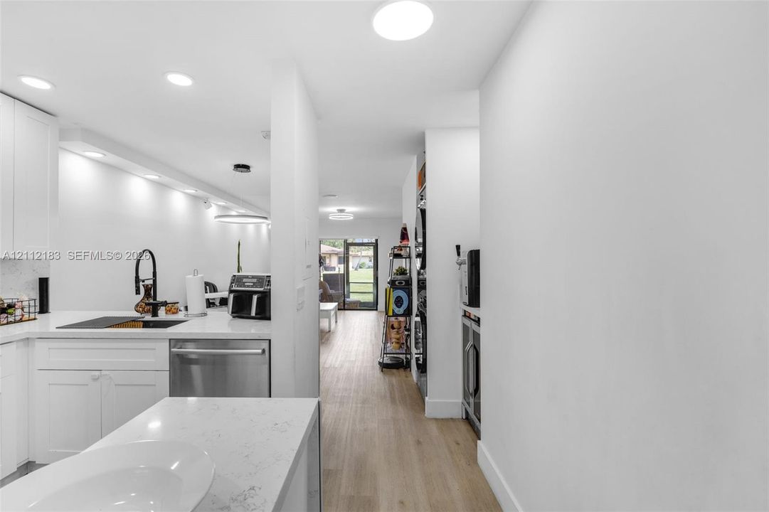 Kitchen featuring white cabinetry, quartz countertops, stainless steel appliances, matte black hardware, and wood-finish flooring