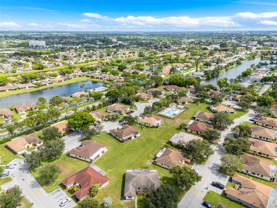 Aerial perspective featuring multi-unit residential structures, mature canopy trees, manicured lawns, and integrated water features
