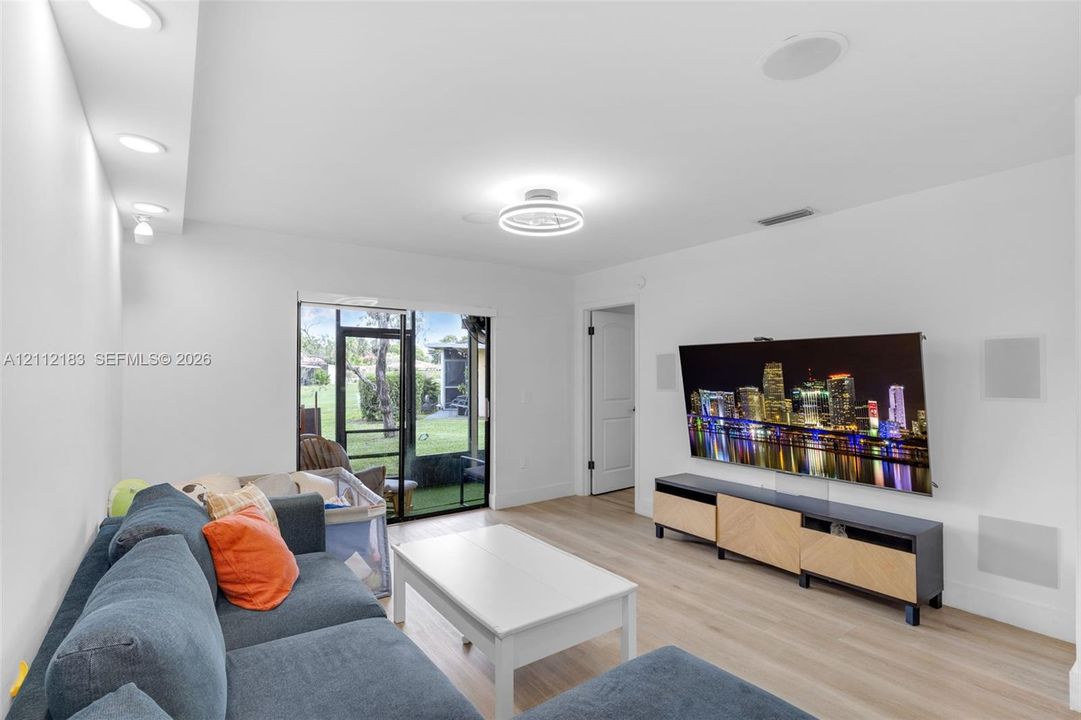 Interior featuring wood-finish flooring, recessed lighting, a modern ceiling-mounted fixture, and sliding glass doors with screen enclosure