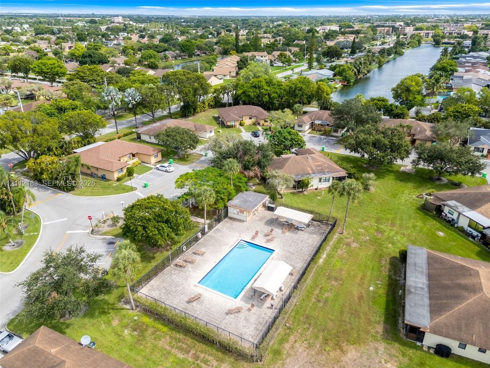 Community swimming pool featuring a paved deck and shaded seating structures