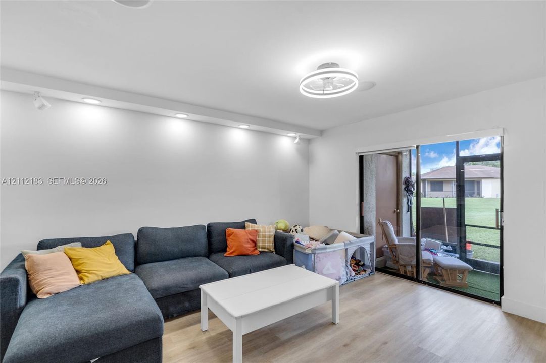 Wood-finish flooring, integrated recessed lighting, circular ceiling fan with light, and sliding glass doors with exterior access