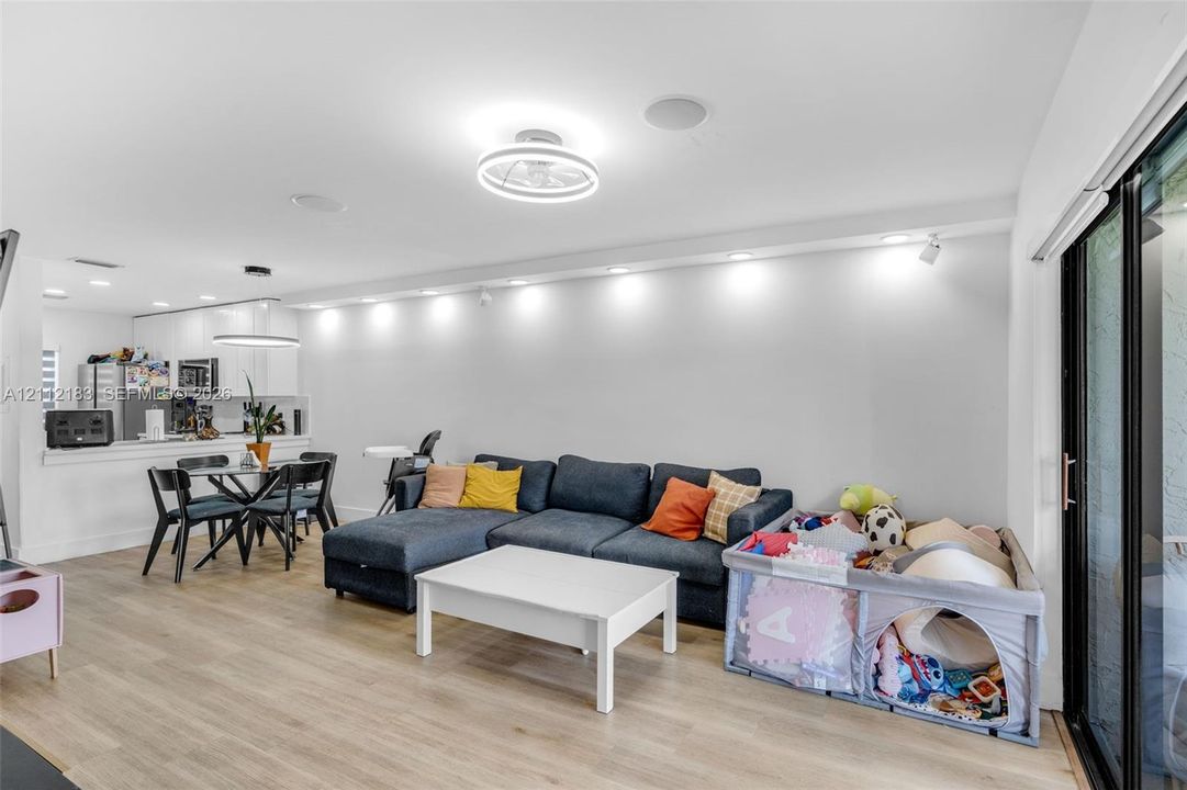 Open-concept floor plan featuring wood-finish flooring, recessed lighting, ceiling-mounted light fixtures, and a glass sliding door