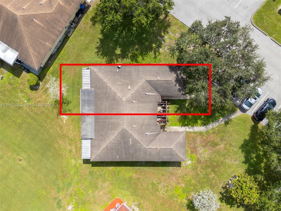 Aerial view of a multi-faceted shingle roof featuring a recessed building footprint and integrated exterior structure