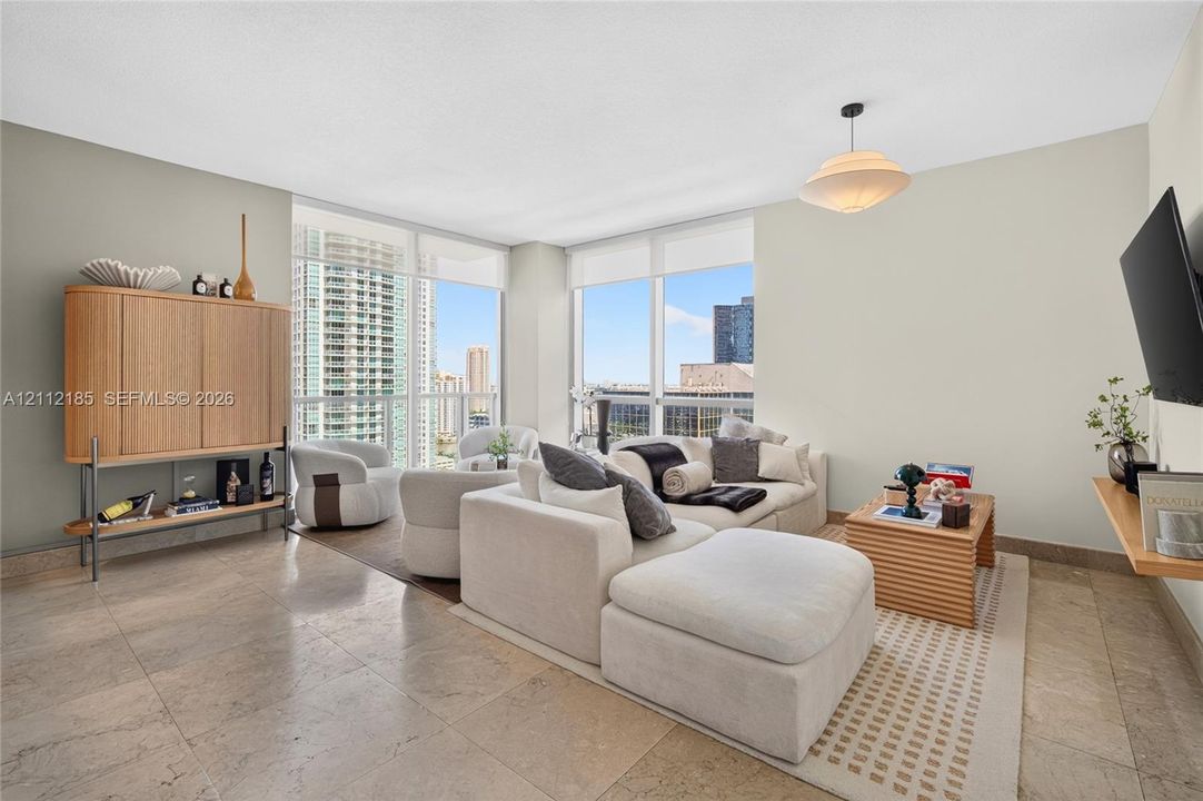 Living area featuring floor-to-ceiling windows, natural stone flooring, and a pendant light fixture