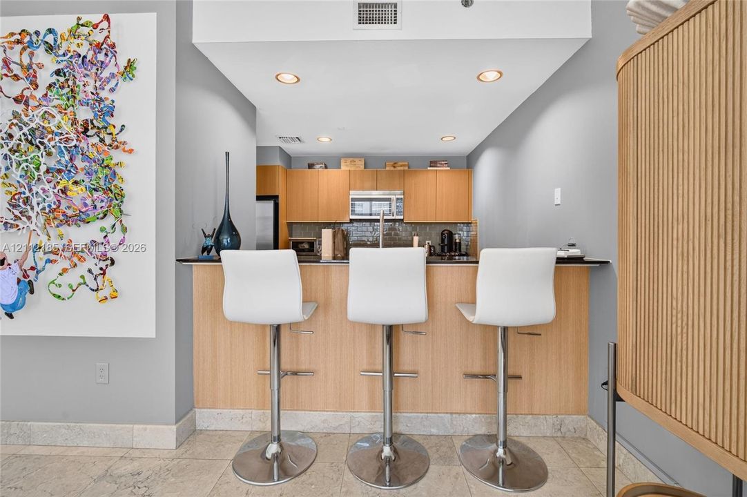 Kitchen featuring flat-panel wood cabinetry, dark stone countertops, built-in microwave, recessed ceiling lighting, and tile flooring