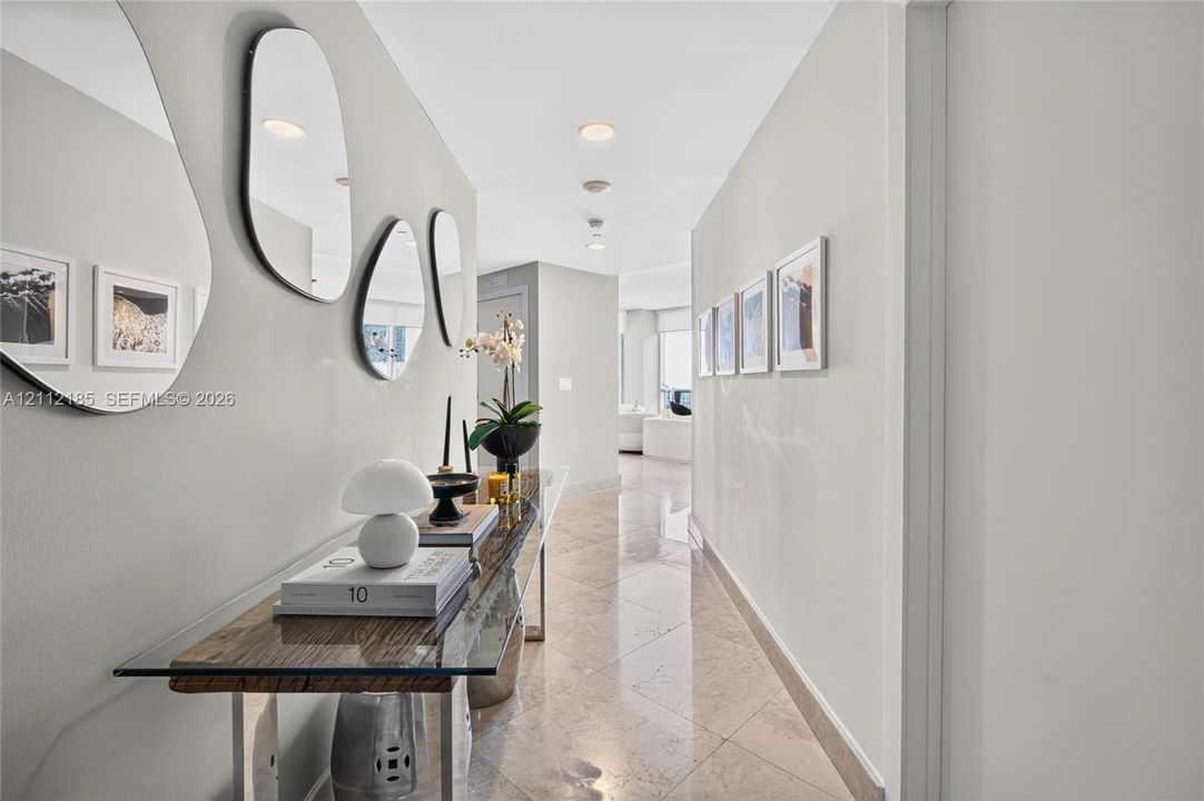Interior hallway featuring polished stone flooring, recessed ceiling lighting, and neutral-toned wall paint