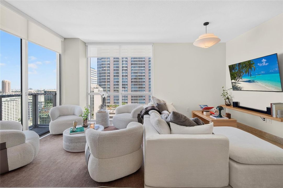 Living area featuring floor-to-ceiling windows, natural light, a wall-mounted wooden shelf, and a pendant light fixture