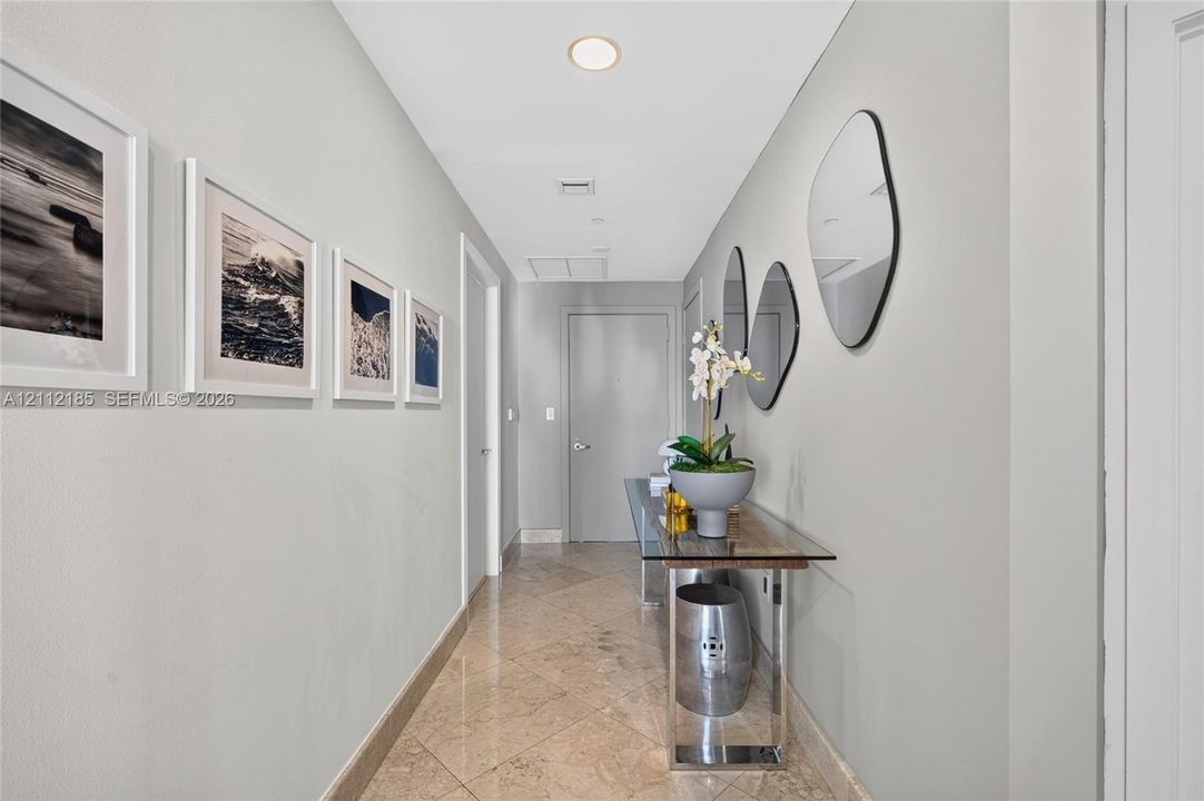 Hallway featuring polished stone-finish tile flooring, recessed ceiling lighting, and solid-core interior doors