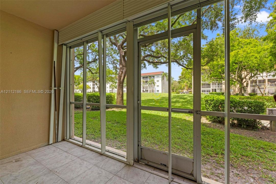 Enclosed patio featuring floor-to-ceiling screen panels, a metal-framed screen door, and ceramic tile flooring