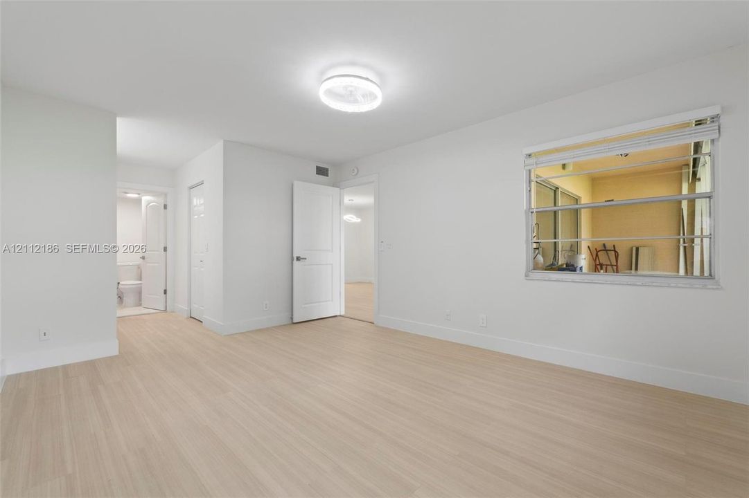 Interior room featuring light wood-finish flooring, neutral wall tones, multi-pane horizontal sliding windows, and a flush-mount ceiling light fixture