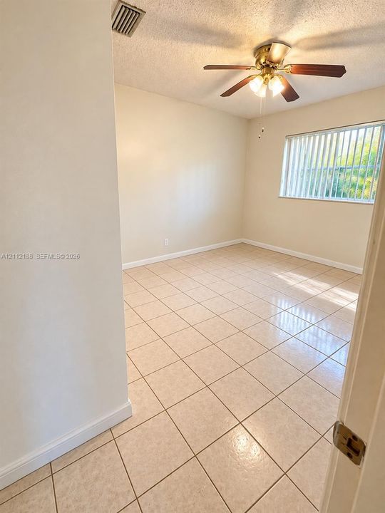 Neutral-toned tile flooring, multi-blade ceiling fan with integrated light fixture, and horizontal window blinds