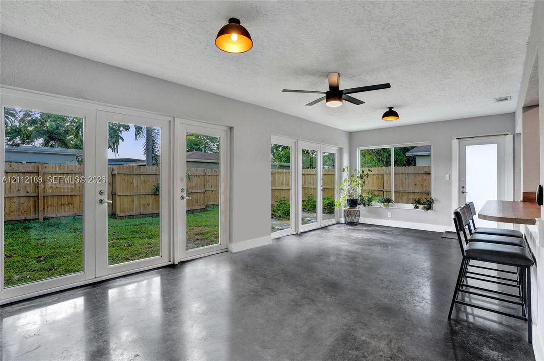 Polished concrete flooring, multiple glass-paneled exterior doors, a built-in breakfast bar, and industrial-style dome pendant lighting