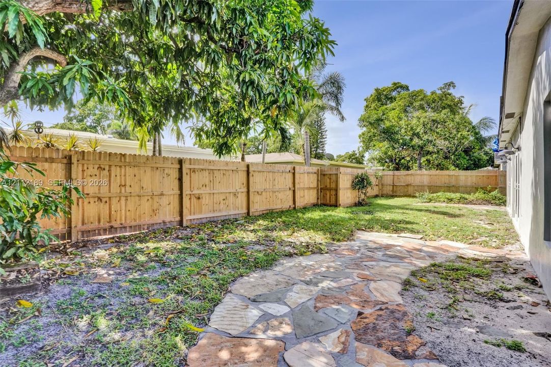 Private backyard featuring a natural stone pathway, wood-style privacy fencing, and mature trees