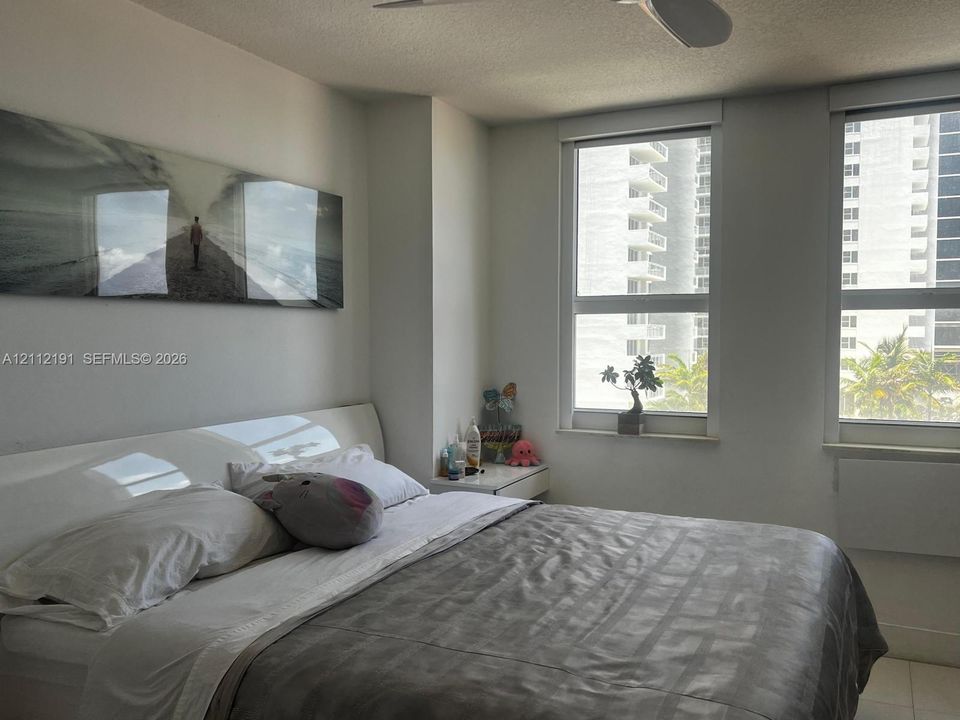 Neutral-toned interior featuring dual oversized windows, light-colored tile flooring, and a white ceiling-mounted fan