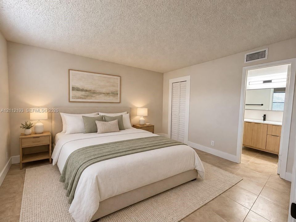 Neutral-toned interior featuring tiled flooring, a textured ceiling, and louvered closet doors