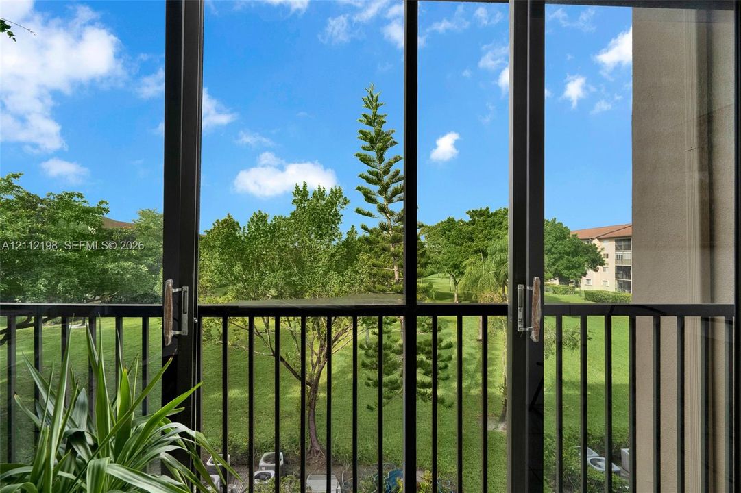 Sliding glass door with a dark metal frame and vertical-bar balcony railing