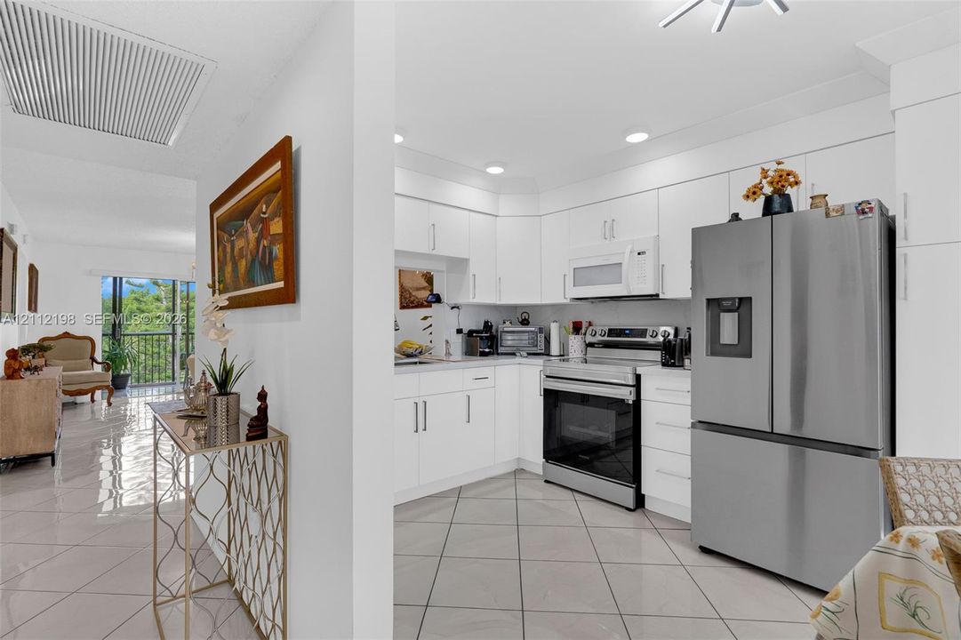 Kitchen featuring white flat-panel cabinetry, stainless steel appliances, and large-format tile flooring