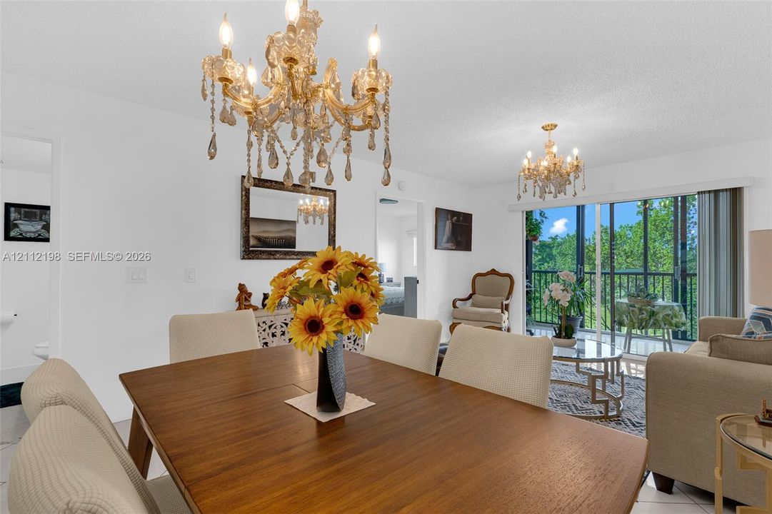 Dual tiered crystal chandeliers, large-format tile flooring, and floor-to-ceiling sliding glass doors leading to a private balcony