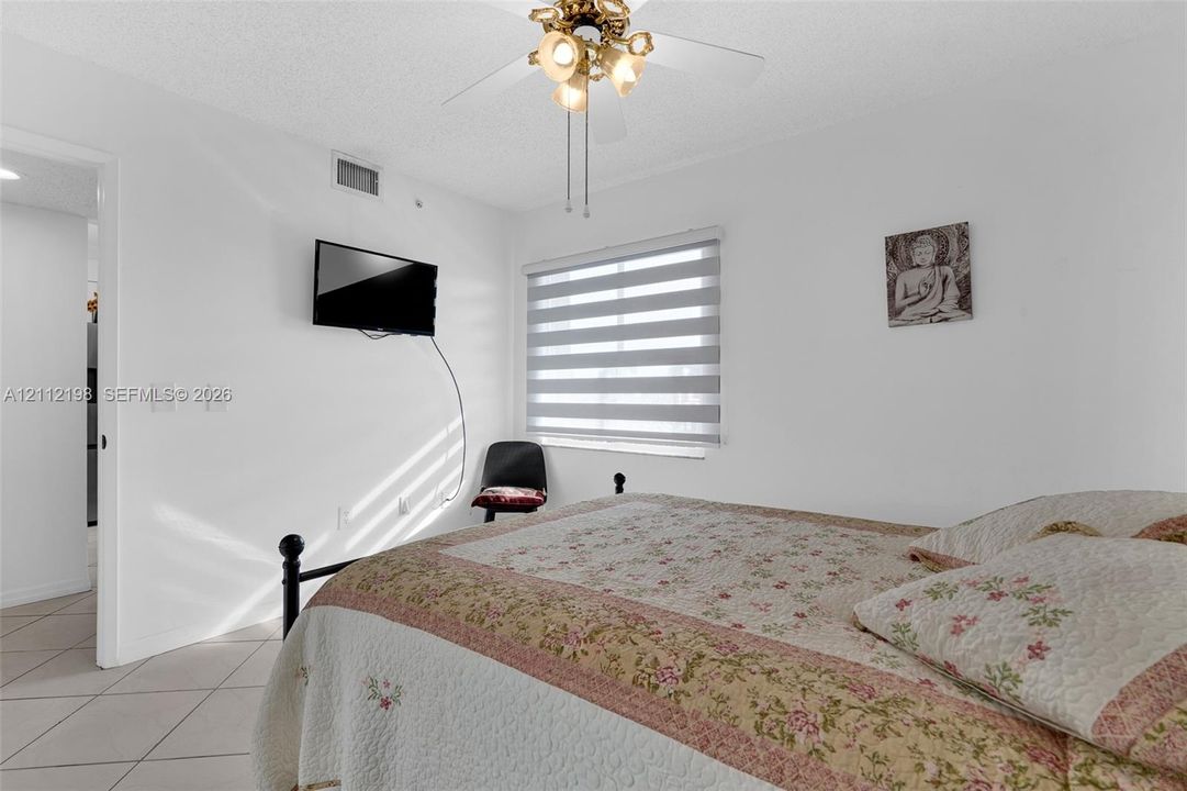 Neutral interior space featuring tile flooring, a multi-light ceiling fan, and window-fitted light-filtering dual shades