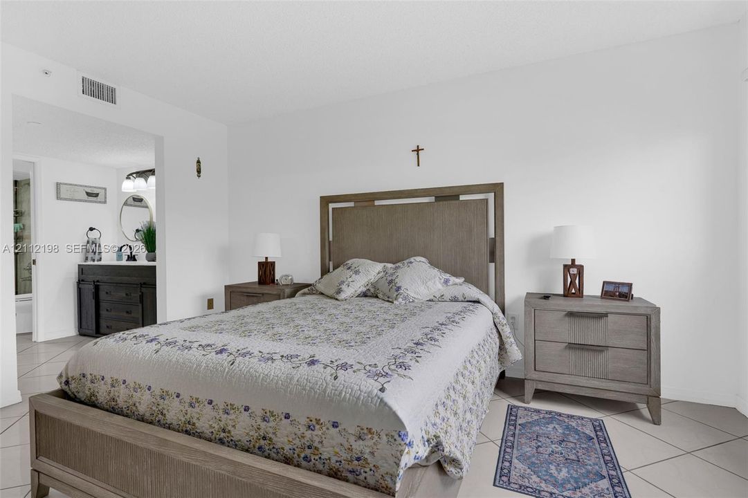 Neutral tile flooring throughout with a dark-finish wood cabinetry vanity and round mirror fixture