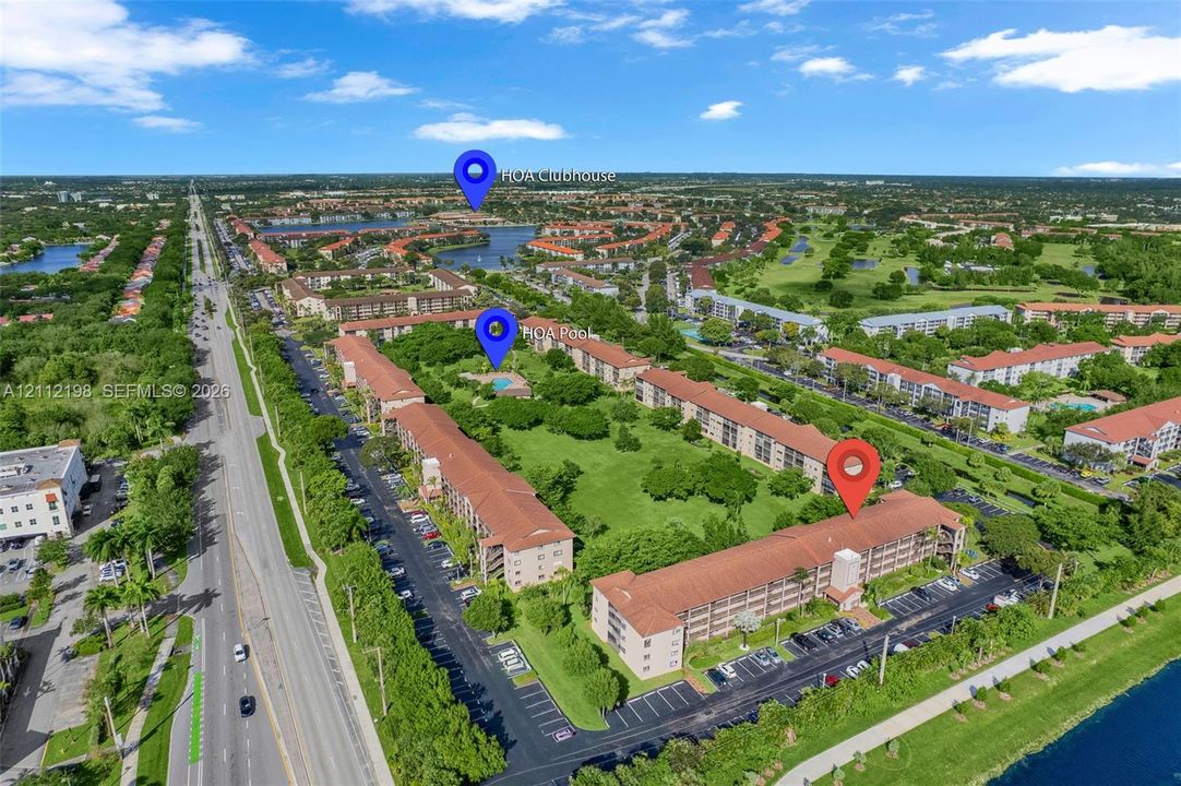 Aerial perspective of a multi-story residential complex featuring red-tile roofing, surface parking lots, and landscaped green space