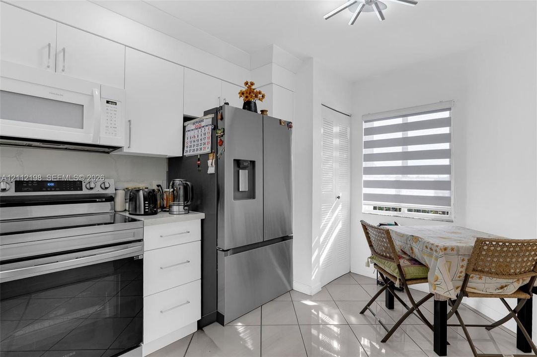 Kitchen featuring white cabinetry, stainless steel appliances, tile flooring, and integrated lighting