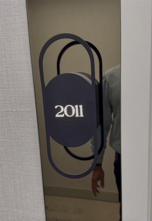 Modern metallic door plaque featuring a matte black geometric frame and integrated Braille signage