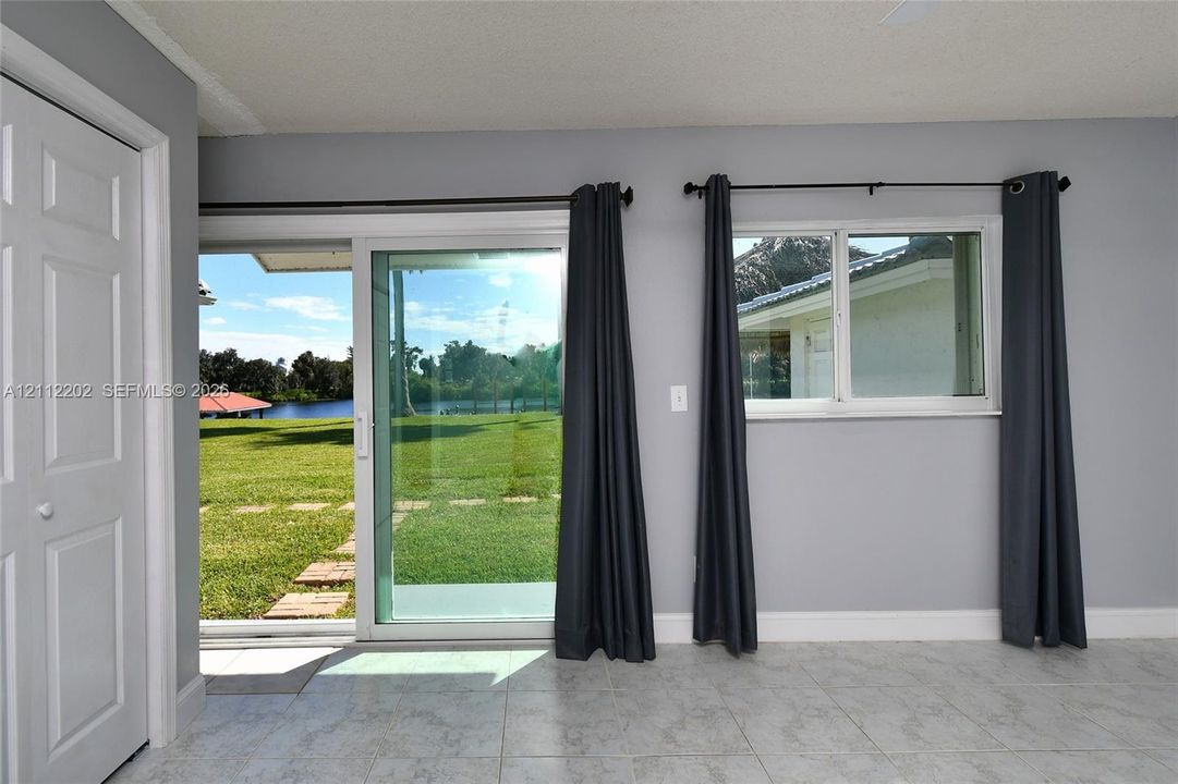 Sliding glass door, single-hung window, light-toned tile flooring, and neutral grey wall paint