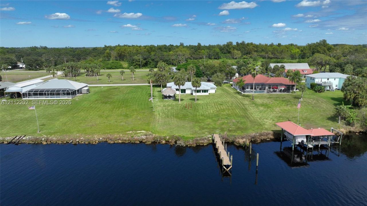 Waterfront property featuring extensive lawn space, a private dock, and a boat lift
