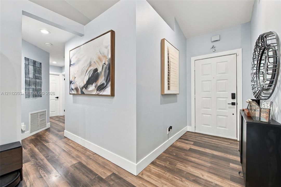 Entryway featuring wood-finish flooring, a white paneled door with integrated electronic lock, and recessed ceiling lighting