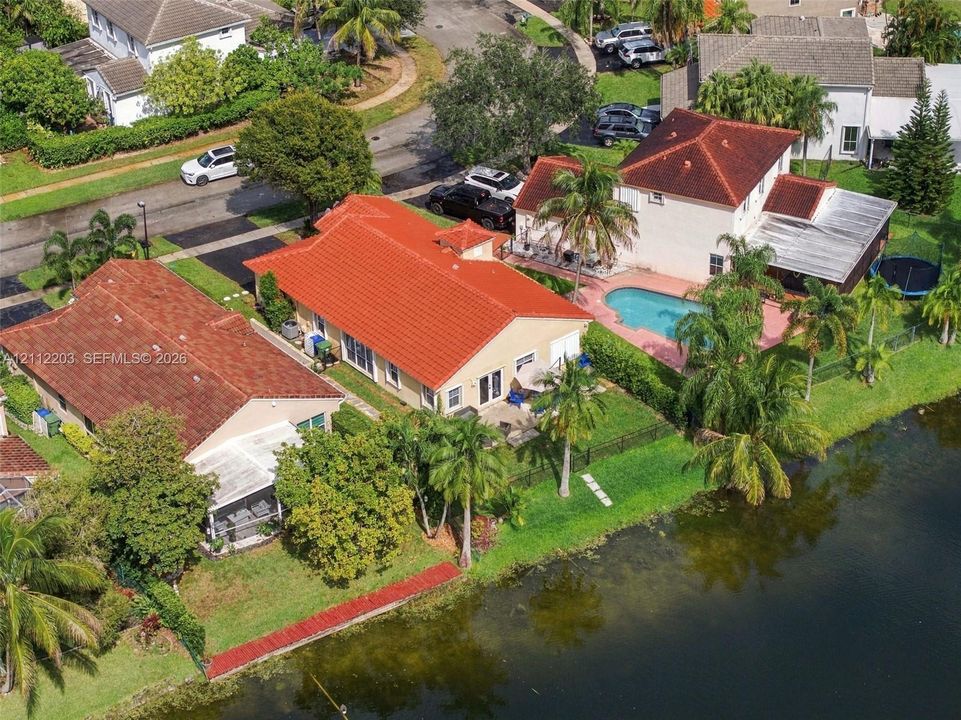 Waterfront residential property featuring a tile roof, expansive rear lawn, and mature landscaping