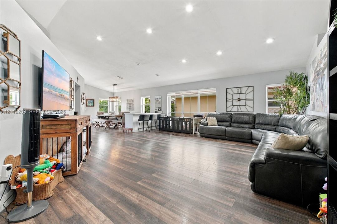 Open-concept room featuring wood-finish flooring, vaulted ceilings, recessed lighting, and large windows