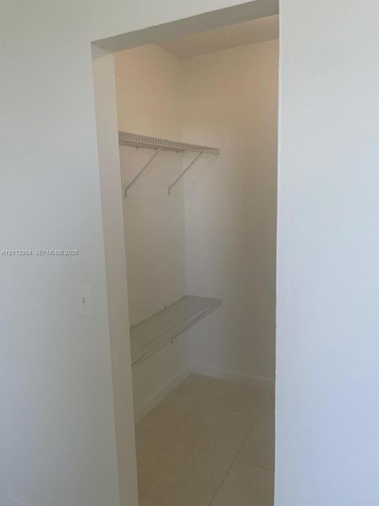 Walk-in closet featuring light-colored tile flooring and two-tier wire shelving