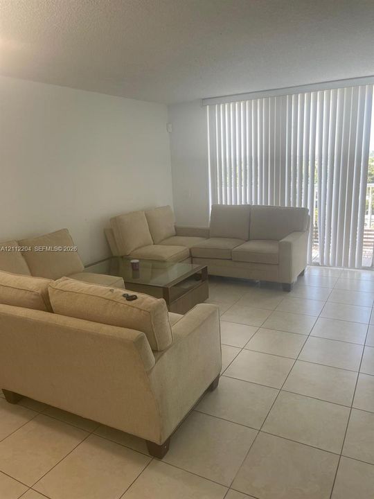 Neutral-toned ceramic tile flooring and floor-to-ceiling vertical blinds