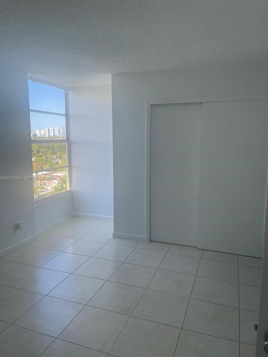 Floor-to-ceiling multi-panel windows, ceramic tile flooring, and a built-in sliding door closet
