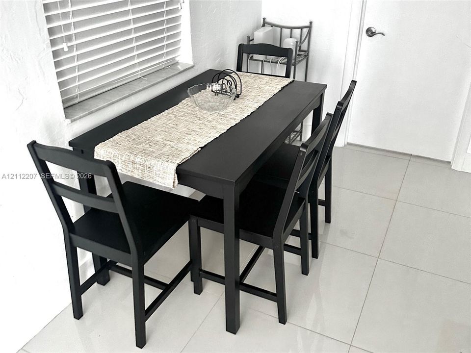 Large-format tile flooring, horizontal slat window blinds, and a neutral wall finish