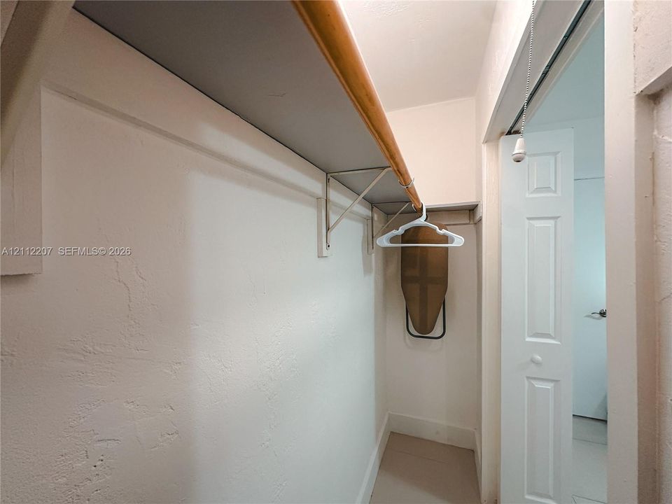Reach-in closet featuring built-in shelving with wood trim and a bifold door