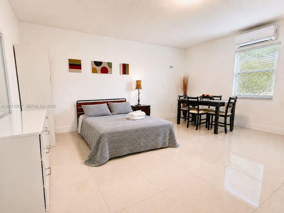 Room featuring neutral tile flooring, white wall finishes, and a wall-mounted ductless air conditioning unit
