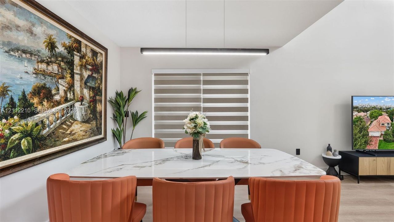 Dining area featuring neutral wall paint, wood-finish flooring, a contemporary linear pendant light, and horizontal window shades