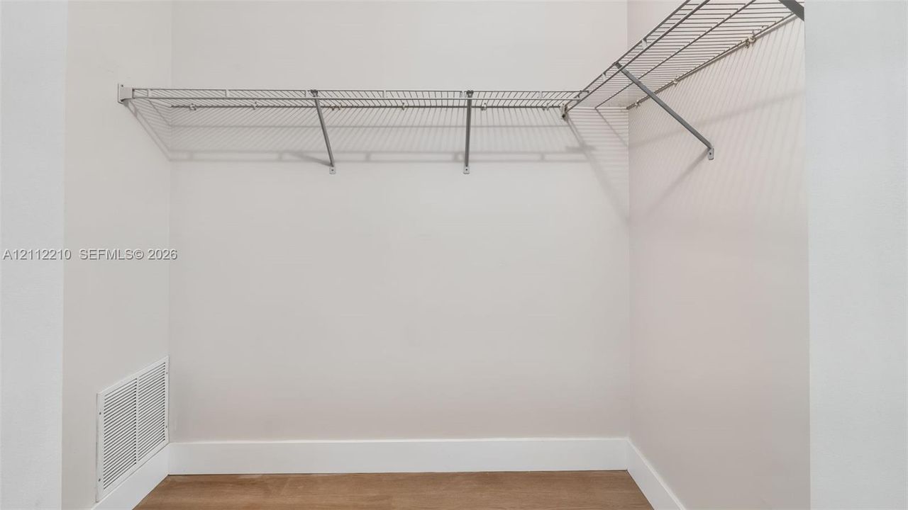 Storage area featuring white wall-mounted wire shelving and wood-finish flooring