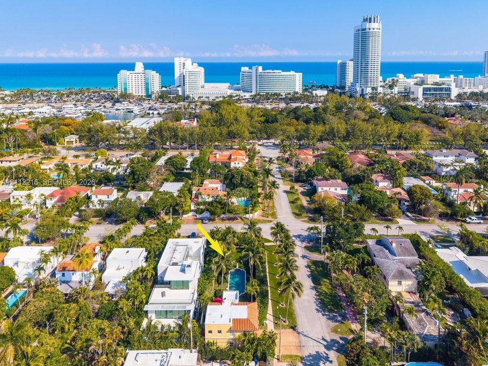 Aerial perspective featuring a multi-story residence with a red-tile roof and a private in-ground swimming pool surrounded by mature palm trees