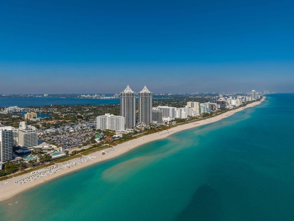 Aerial perspective of a coastal environment featuring extensive sandy beaches, expansive shoreline, and direct proximity to open water