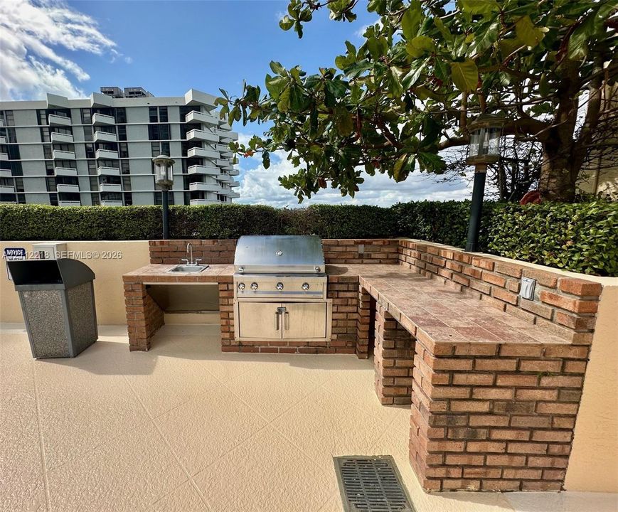 Outdoor grilling station featuring a masonry brick structure, stainless steel built-in grill, integrated prep counters, and a drop-in sink