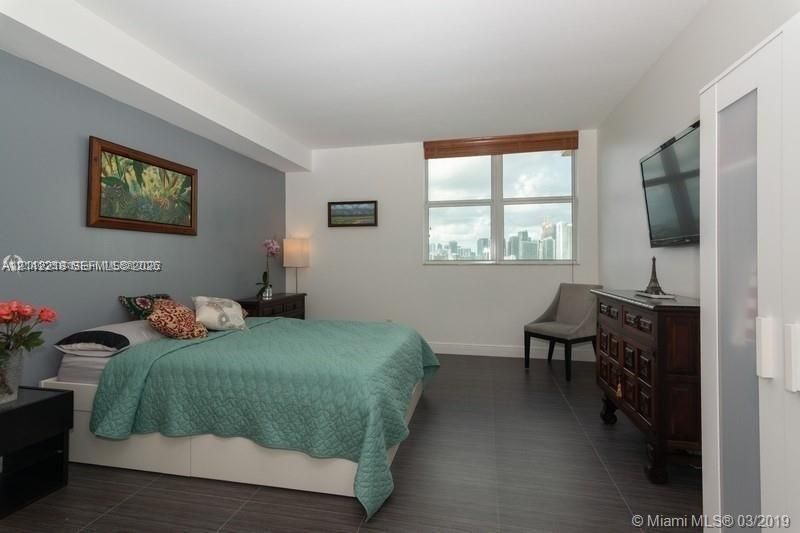 Bedroom featuring dark tile flooring, a neutral color palette, an accent wall, and a large window