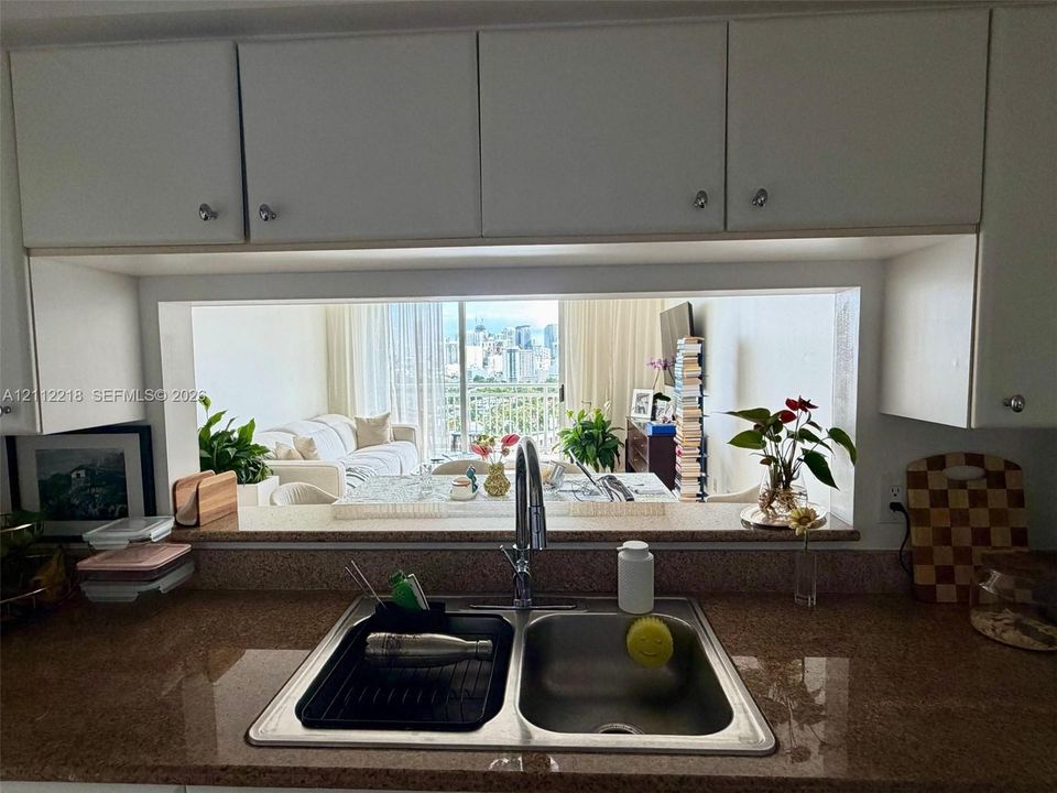 Kitchen featuring white upper cabinetry, stone-finish countertops, and an integrated stainless steel double-basin sink with a gooseneck faucet