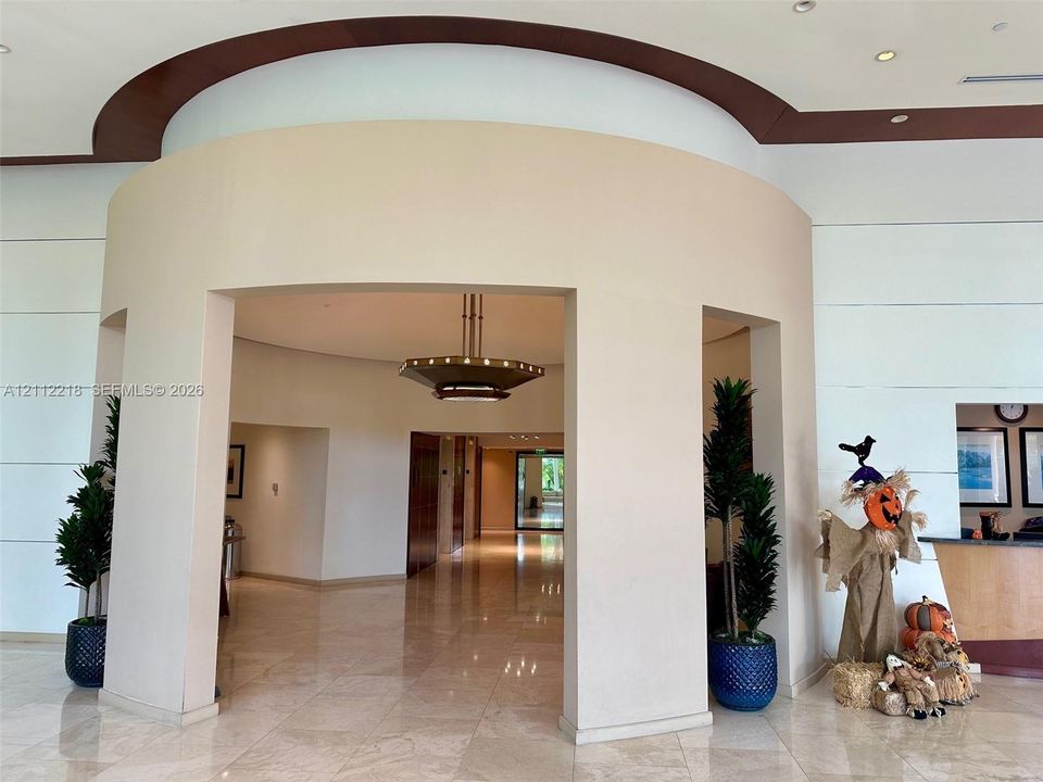 Curved architectural entryway featuring stone tile flooring, recessed ceiling design, and a tiered metal chandelier