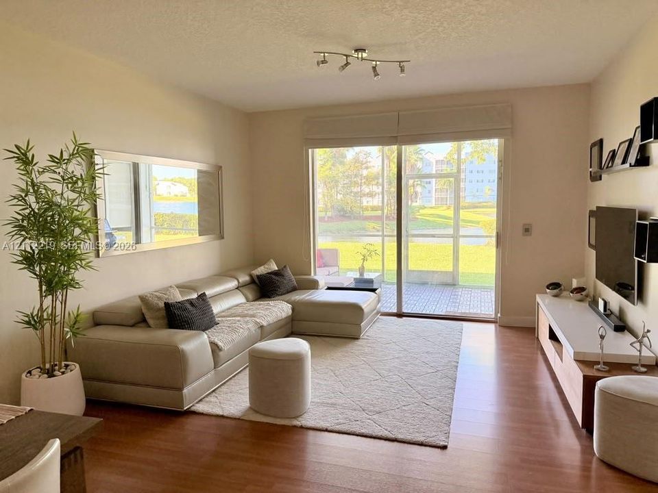 Living space featuring wood-finish flooring, sliding glass doors, built-in media shelving, and a track lighting fixture